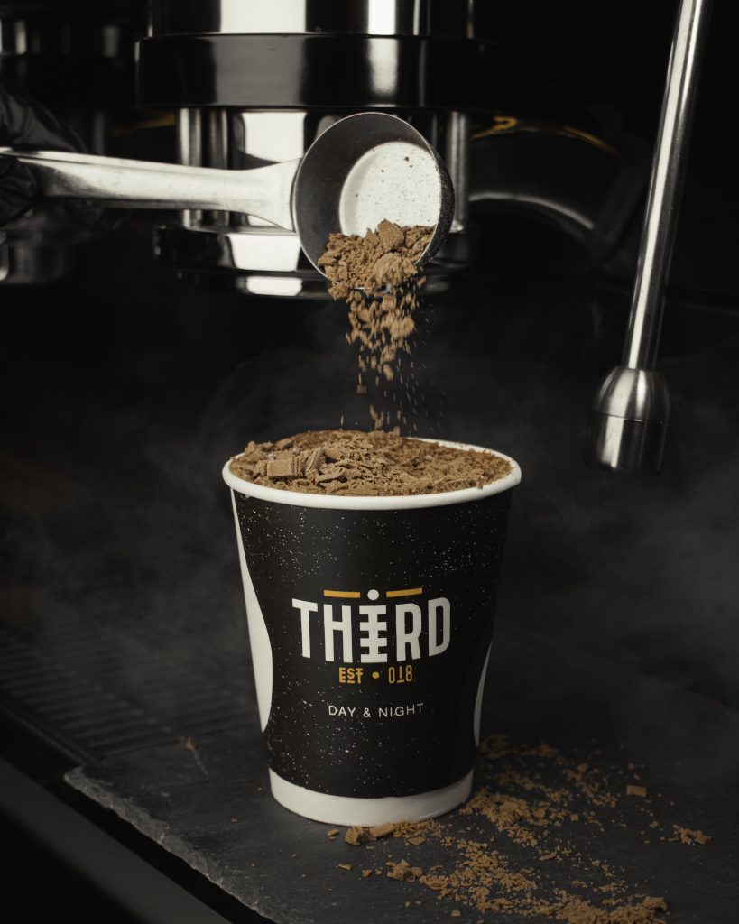 Ground coffee falling into a THiRD cup